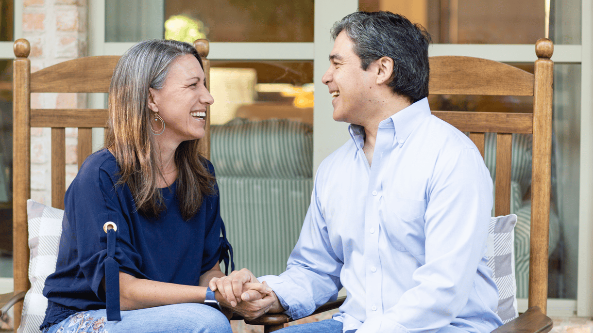 A married couple sitting together and laughing