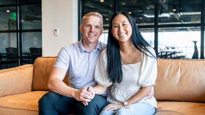 A couple sits on a couch holding hands