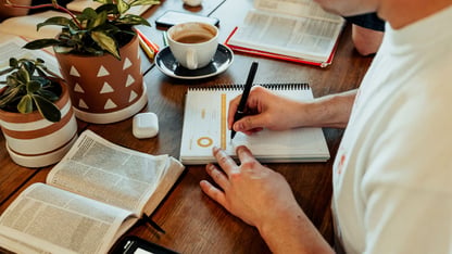 a man reading his bible and writing in a journal