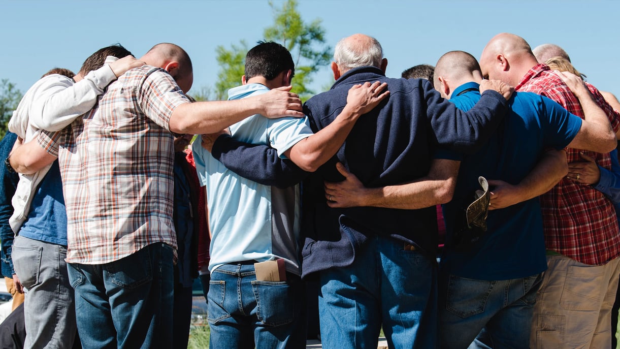 Men standing in a circle praying together