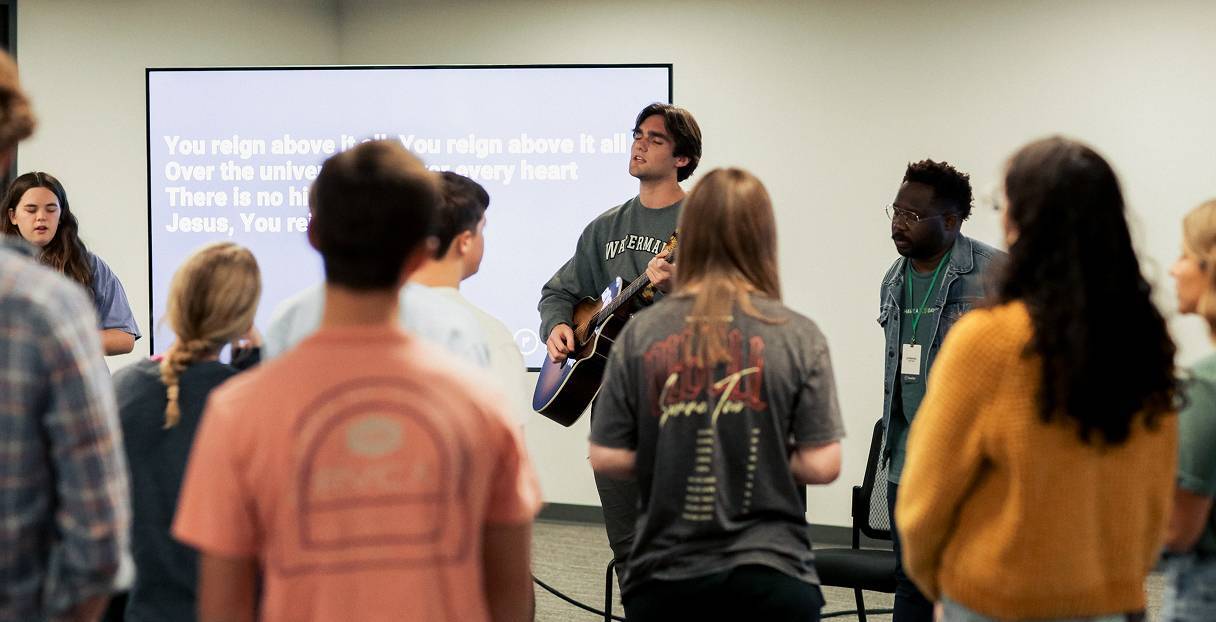 Re:generation for Students leader playing guitar and leading teens in worship